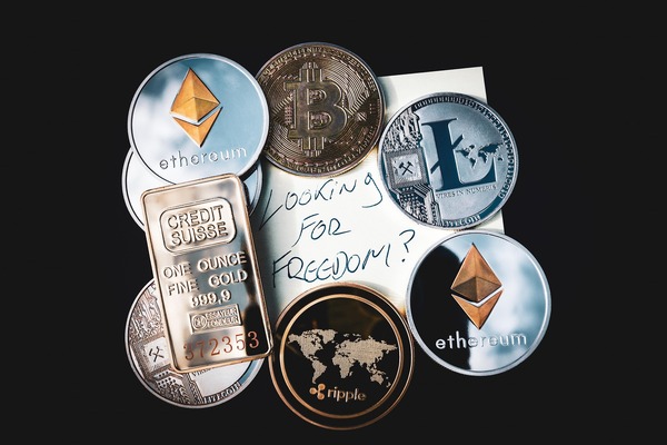 Cryptocurrency coins and a gold bar on a dark background