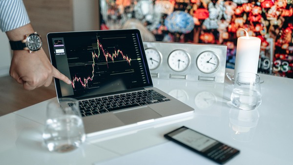 Hand pointing at a price chart on a laptop screen