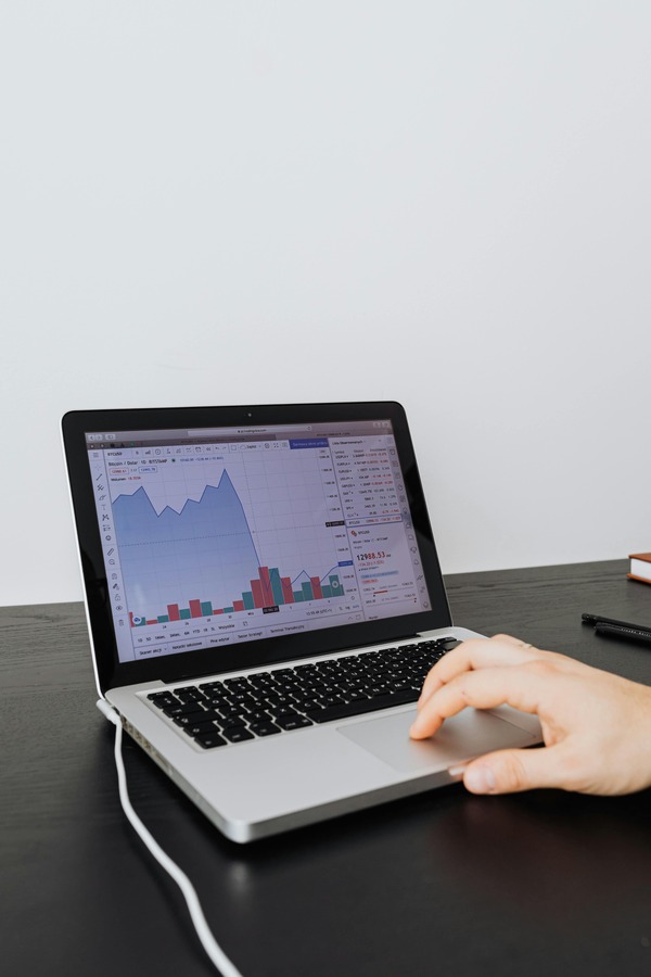 Laptop showing a trading chart on a dark desk