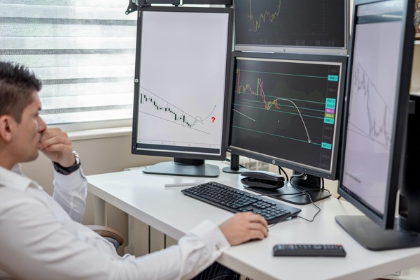 Trader reviewing price charts on several monitors